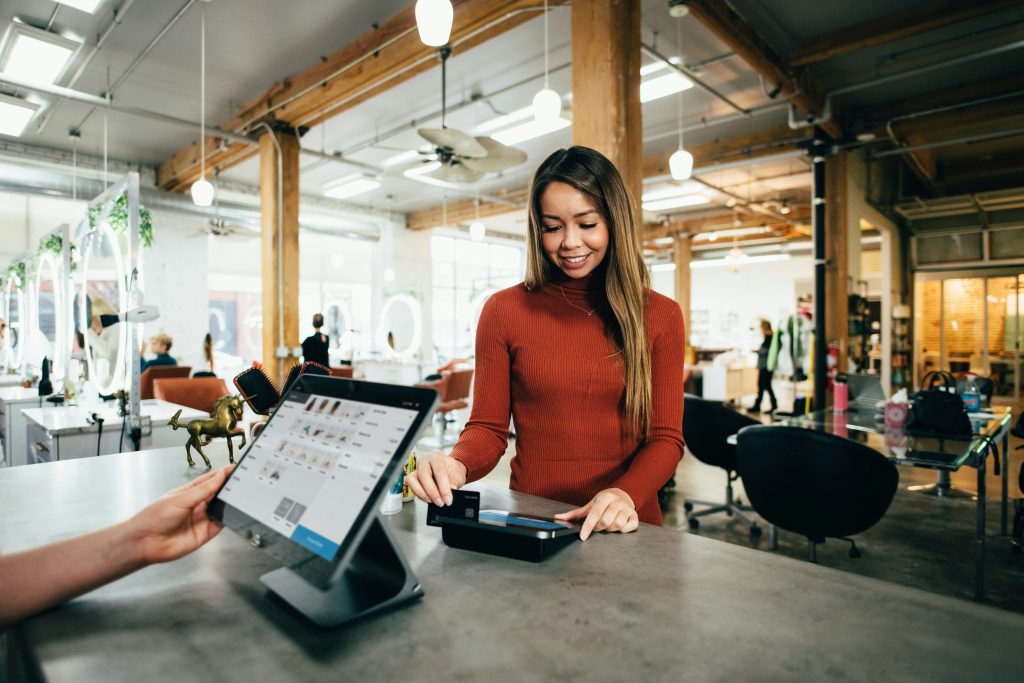 Cliente qui présente sa carte de fidélité au commerçant.
