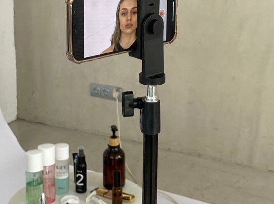 A woman filming a video with a brand's products in the background.