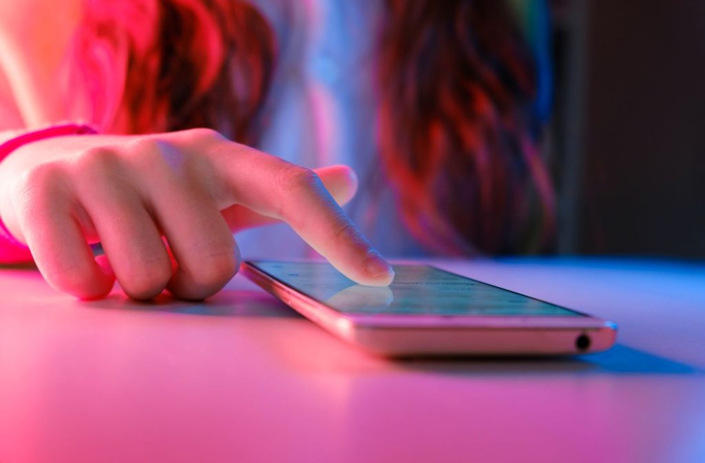 Image d'une fille touchant l'écran de son téléphone à l'aide de son doight.
