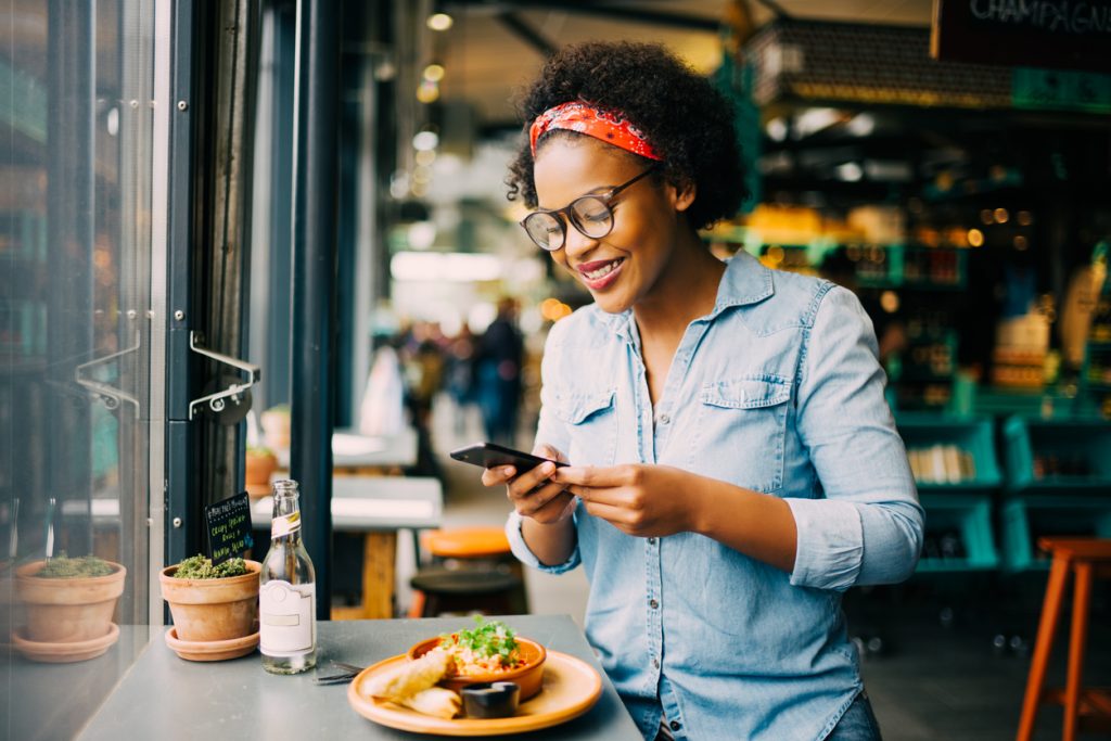 Femme prenant une photo de son assiette dans un restaurant avec son téléphone