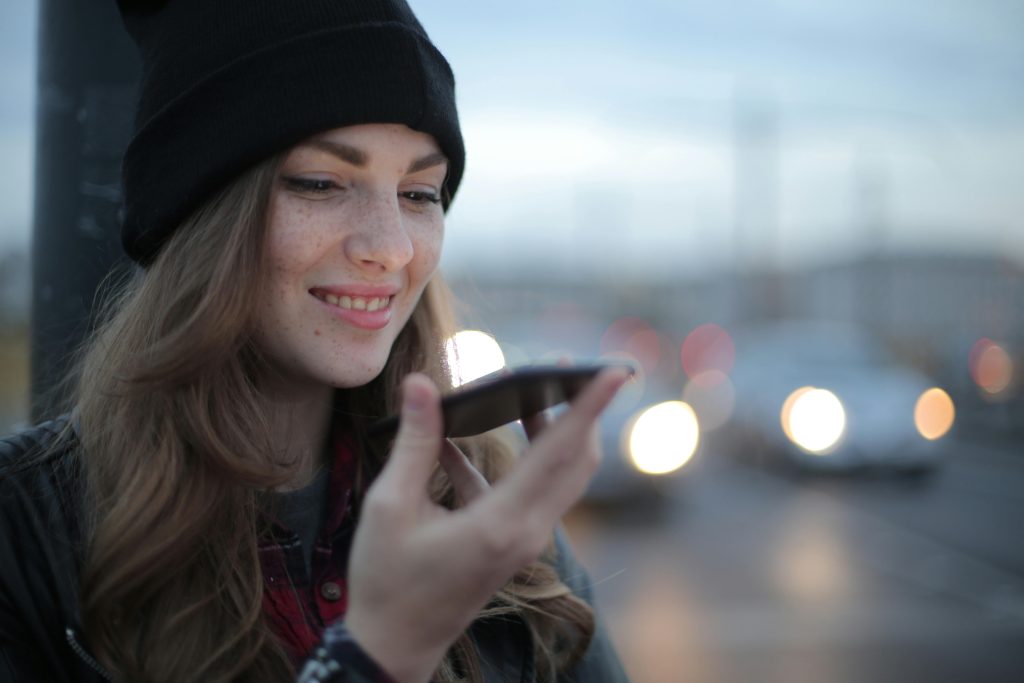 Brunette girl holding a smartphone in a hand and using a voice search