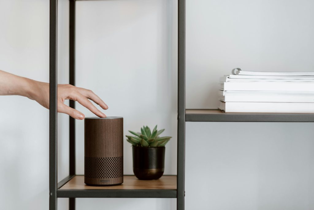 Human hand touching smart speaker on the shelf