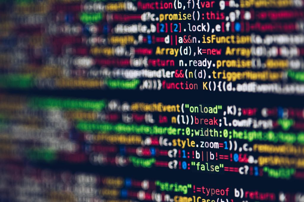 Une image floue montrant du texte coloré de code informatique sur un écran d'ordinateur, suggérant le thème du développement logiciel ou de la programmation.
