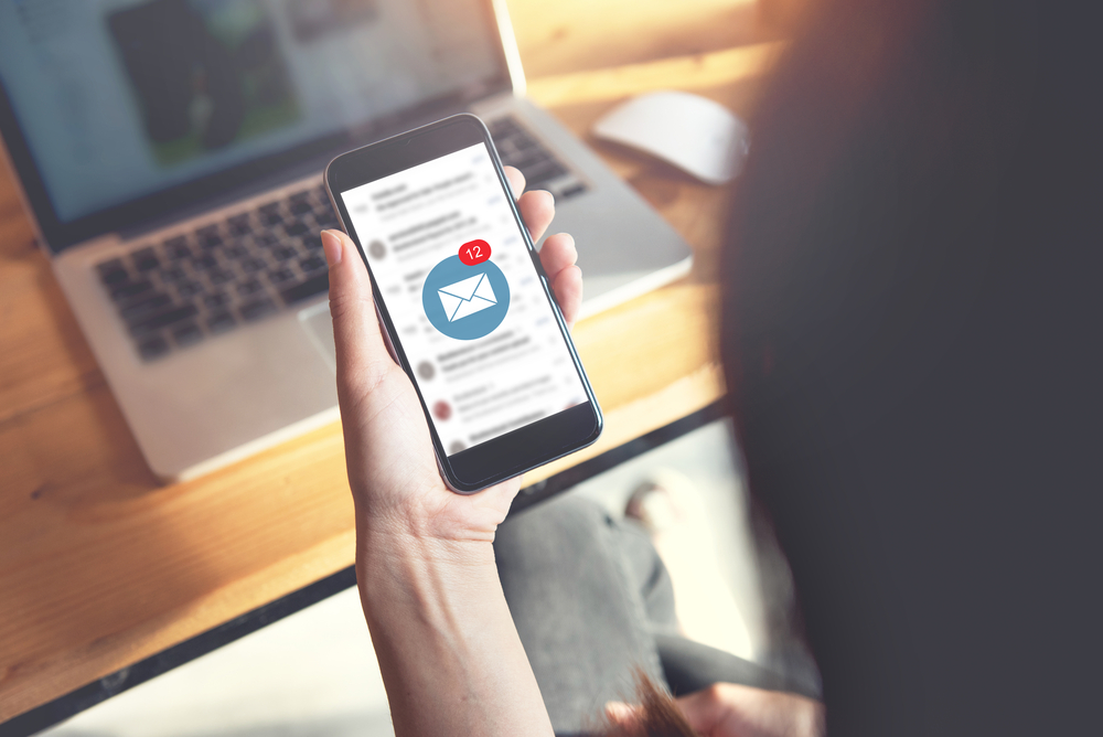 A person checking their email on a smartphone with a notification badge showing unread emails