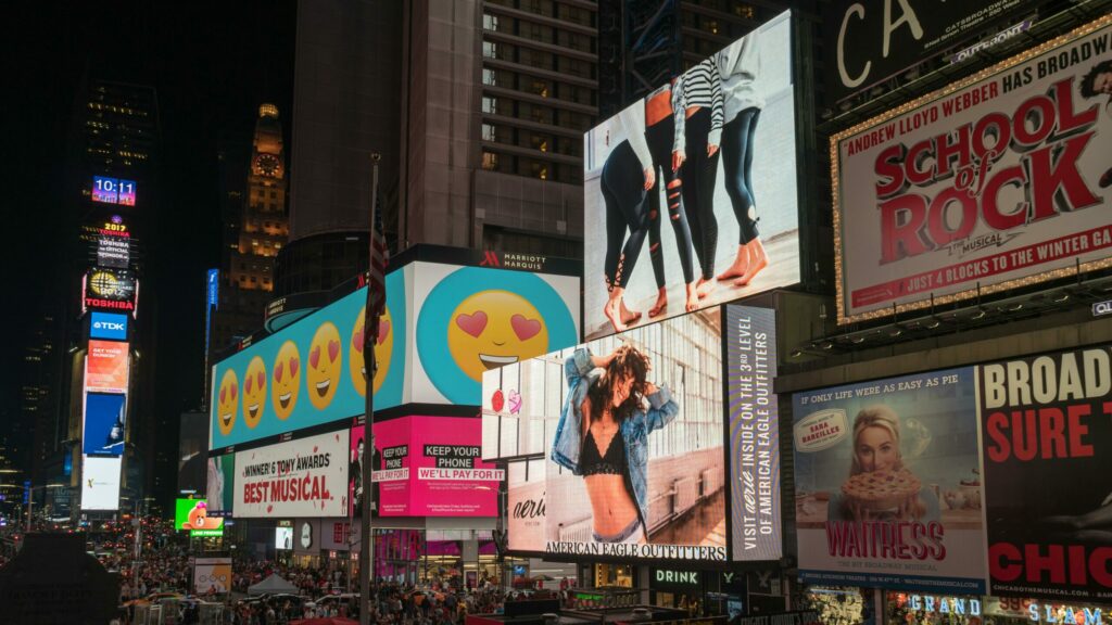 Vue nocturne de Times Square à New York, endroit clé du fake out of home, illuminé par de grands panneaux publicitaires colorés. Une foule de passants se déplace dans la rue en dessous.