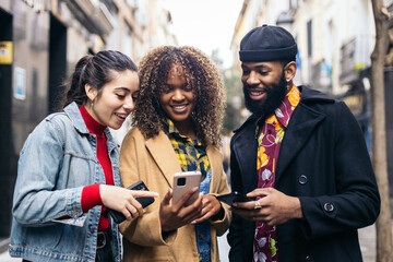 three people standing together smiling and looking at a phone