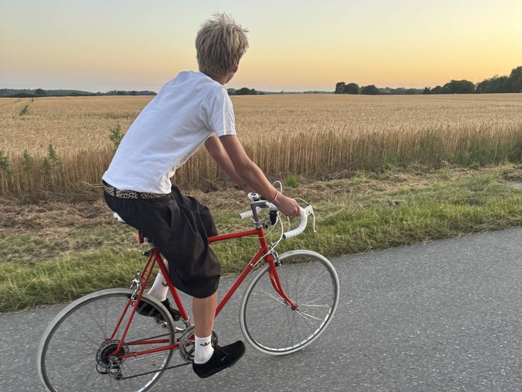 Editorial-style image of a person cycling beside a field at sunset