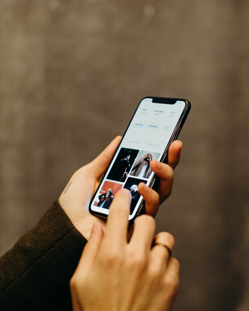 Une personne tient un téléphone à deux mains et fait défiler du contenu sur son écran, illustrant l'aspect addictif de la bulle de filtres.