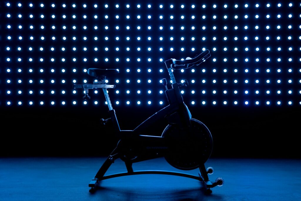 Stationnary bike in a dark blue sultry-looking setting, illustrating Garage's activewear marketing.