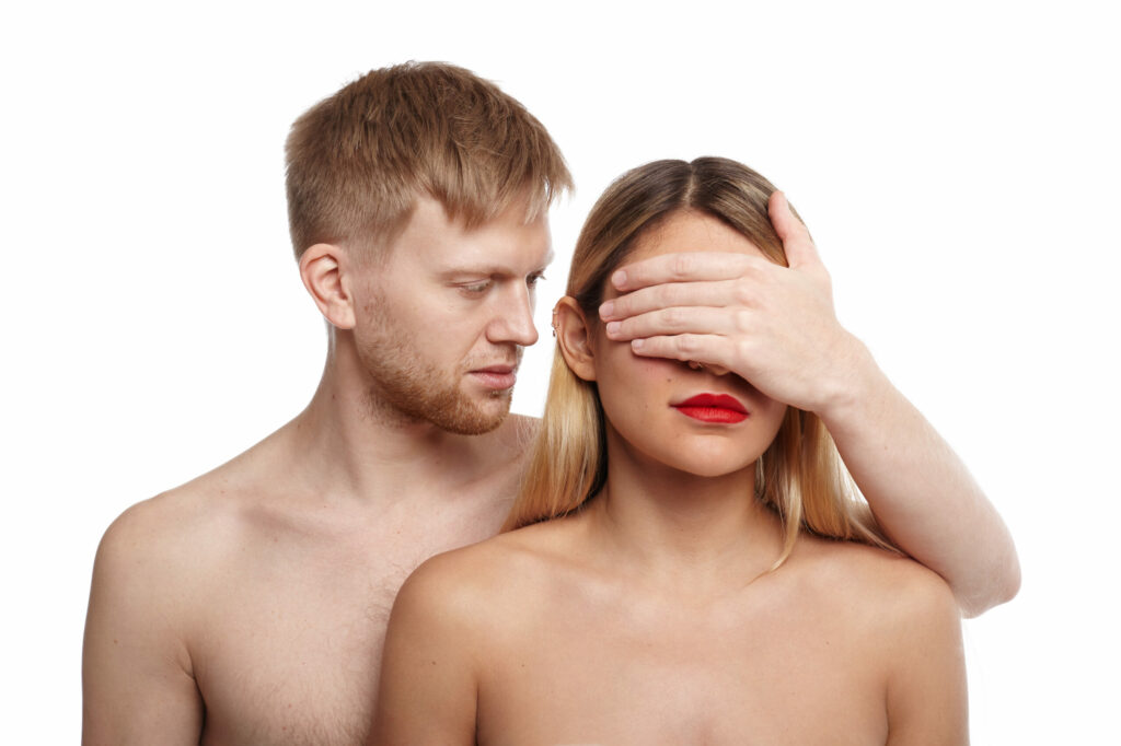 A man hiding a woman's eyes to represent the male gaze and the way women are visually controlled in digital marketing.