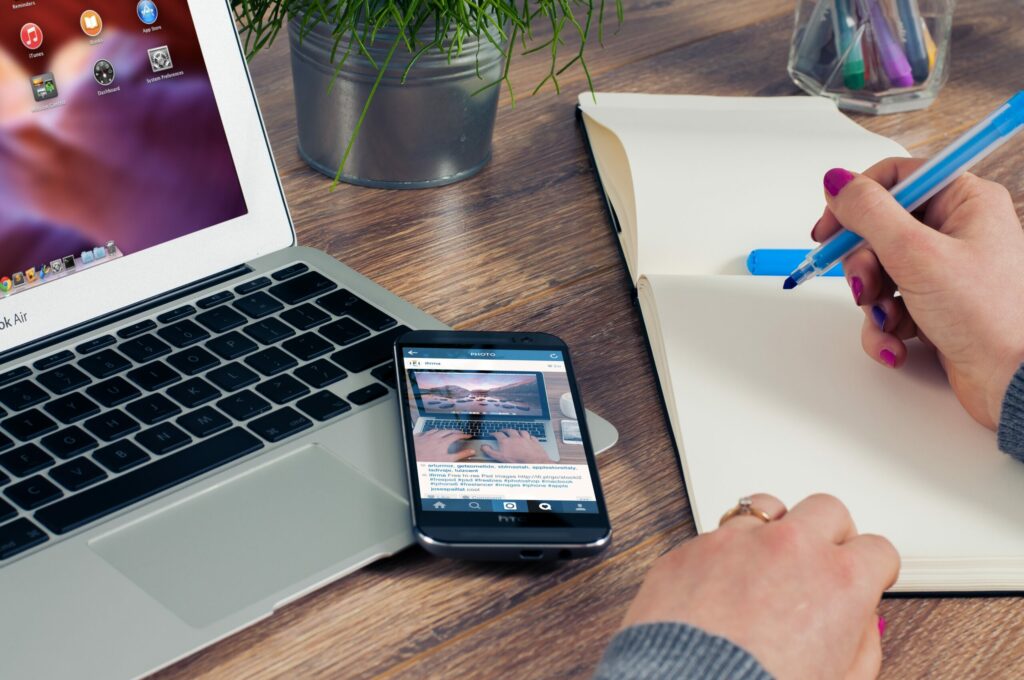 Content creator planning social media content with a smartphone, laptop and a notebook.